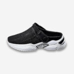 Un sabot orthopédique pour homme avec support de voûte plantaire de couleur noire avec une semelle blanche très épaisse, look sportif vu de profil sur un fond gris très clair uni.