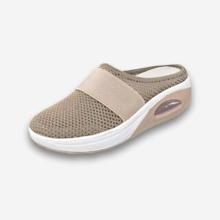 Chaussons orthopédiques en maille aérée pour femme de couleur beige ouvert à l'arrière. Semelle épaisse blanche avec bulle au talon. Sur fond uni clair.
