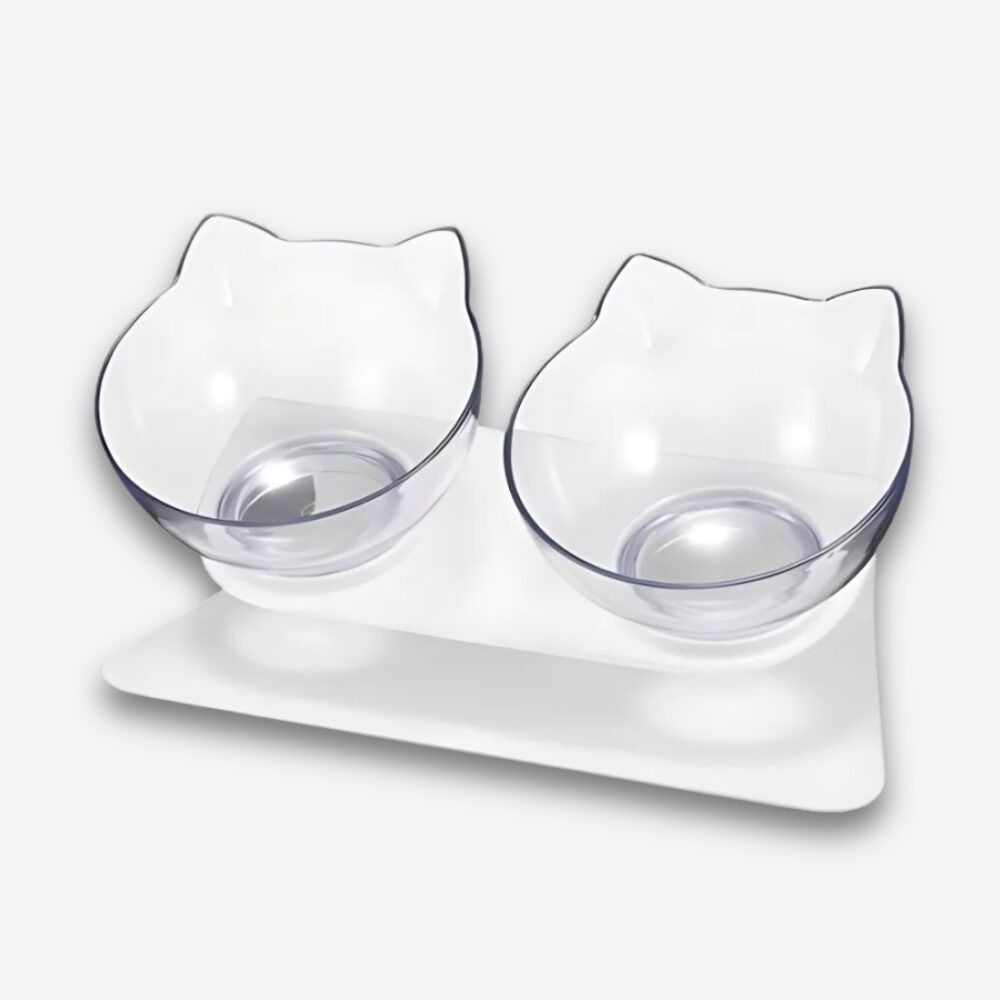 Gamelle orthopédique pour chat double bol incliné. Support blanc et deux bols en forme de tête de chat transparente. Sur fond uni clair.