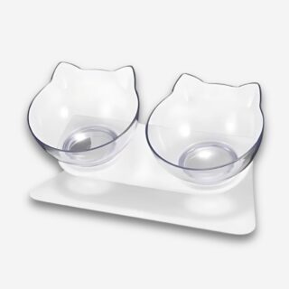 Gamelle orthopédique pour chat double bol incliné. Support blanc et deux bols en forme de tête de chat transparente. Sur fond uni clair.