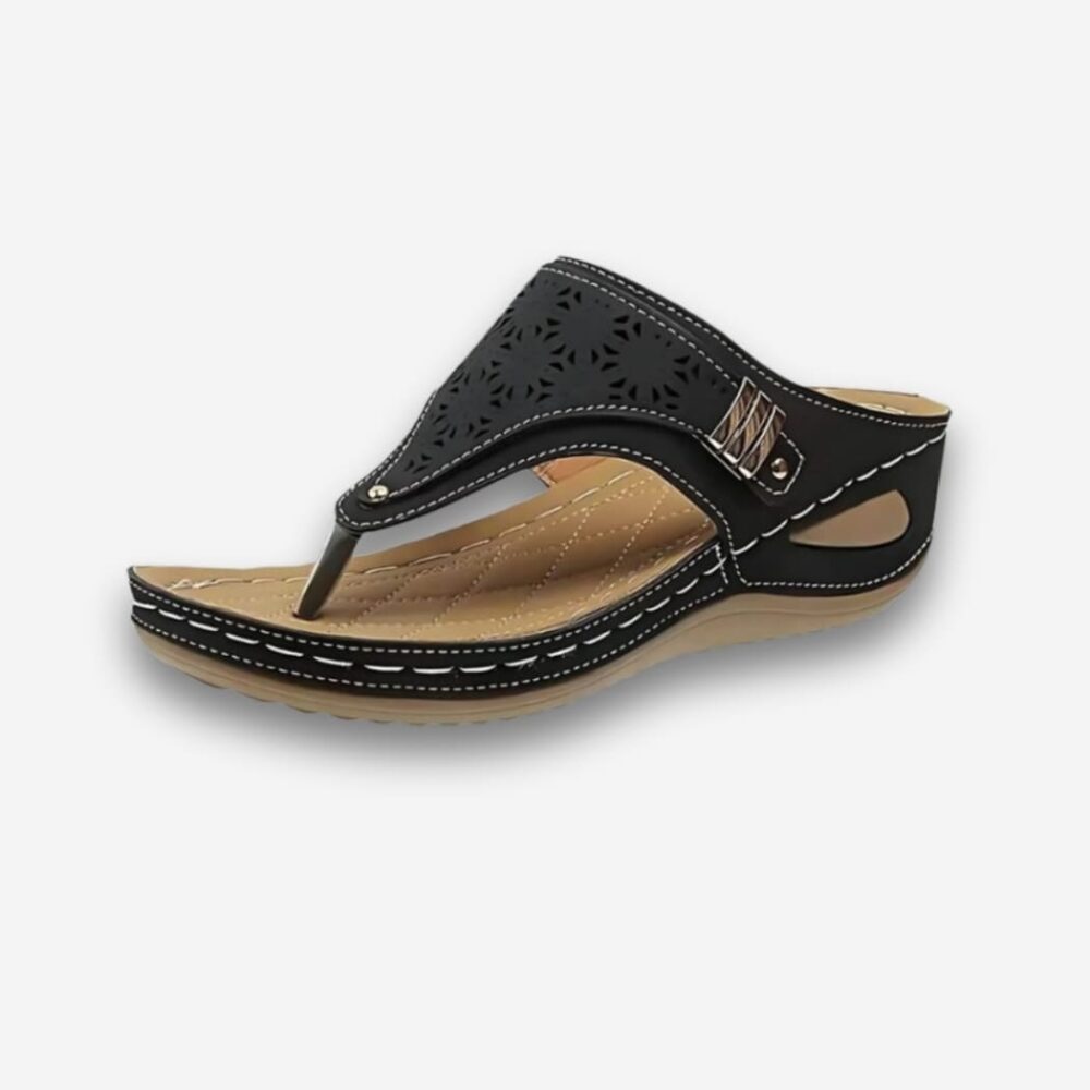 Tongs orthopédiques à talon surélevé pour femme de couleur noire en similicuir. Un détail doré sur le côté de la bride ajourée. Sur fond uni clair.
