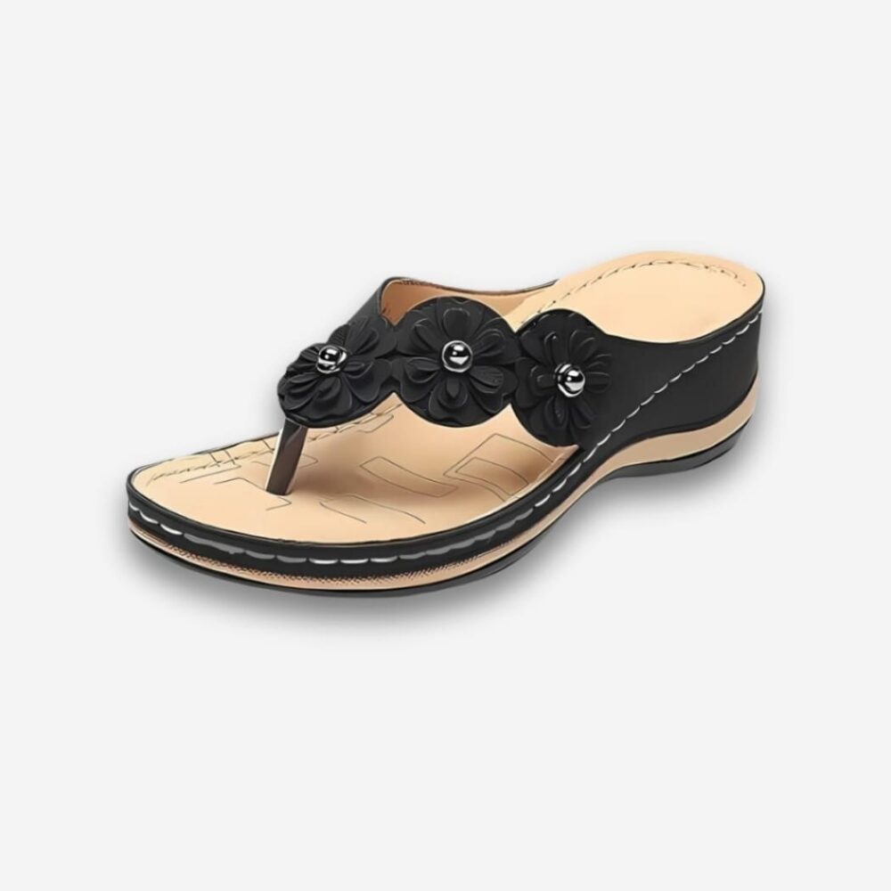 Tongs orthopédiques style bohème pour femme de couleur noire en similicuir avec 3 fleurs en relief sur la bride. Sur fond uni clair.