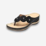 Tongs orthopédiques style bohème pour femme de couleur noire en similicuir avec 3 fleurs en relief sur la bride. Sur fond uni clair.
