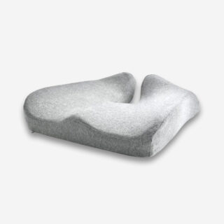 Un coussin orthopédique fessier pour bureau gris, vu de 3/4 sur un fond gris très clair uni.