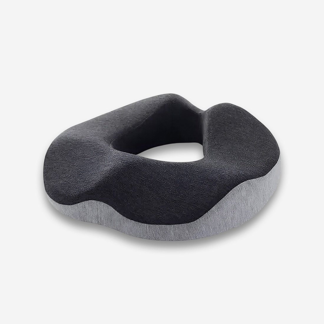 Un coussin orthopédique fessier à mémoire de forme avec une housse de couleur noire & grise disposé de 3/4 sur un fond gris très clair uni.
