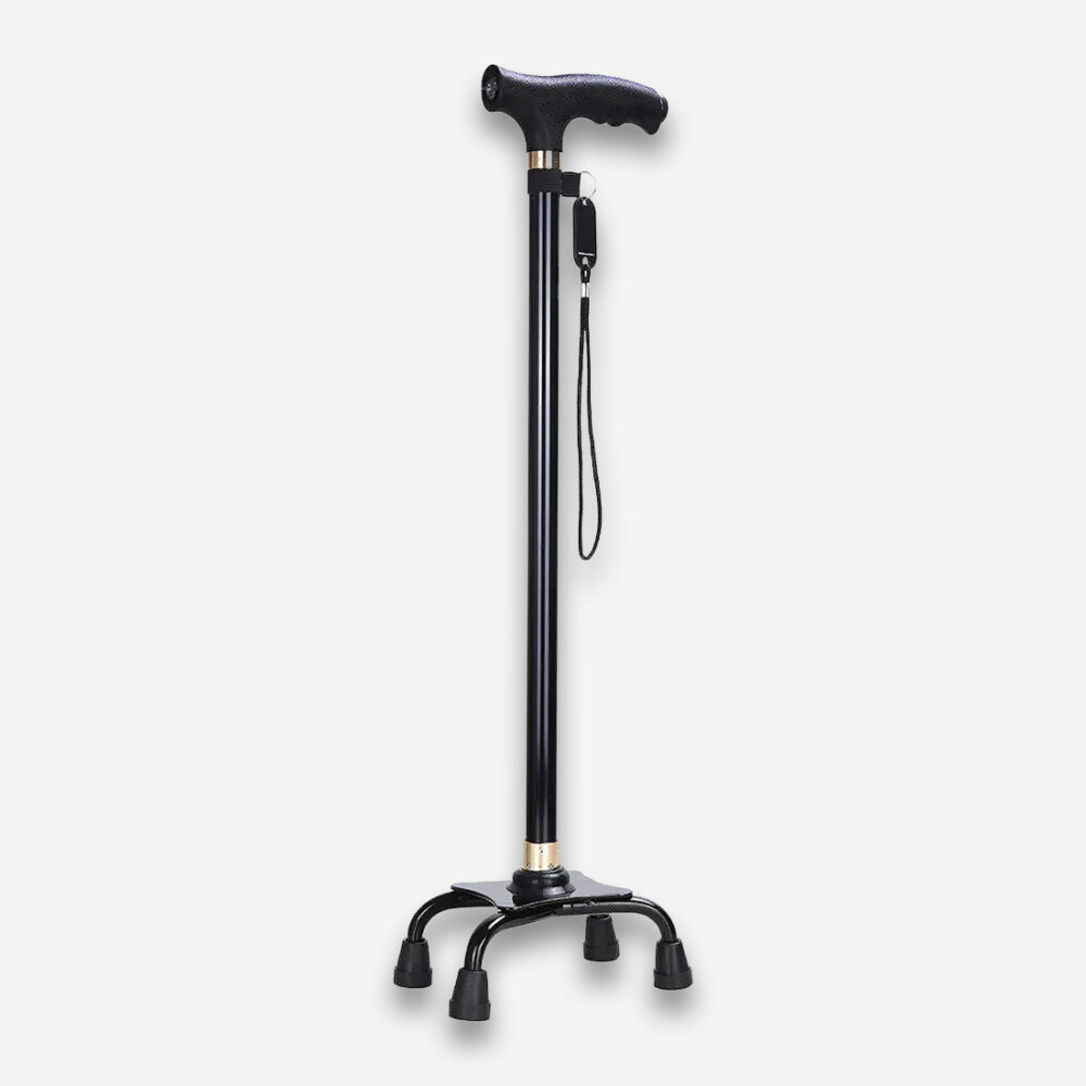 Une canne marche orthopédique antidéparante à base large, entièrement noire avec un corps en aluminium et 4 pieds antidérapants écartés, vue de profil sur un fond gris très clair uni.