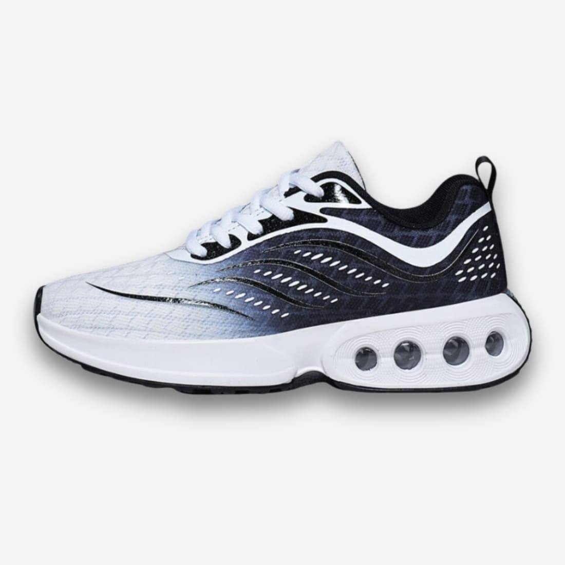 Baskets orthopédiques pour femme à lacets noir et blanche en dégradé, le talon sur la droite avec une semelle blanche et des bulles transparentes. Sur fond uni clair.