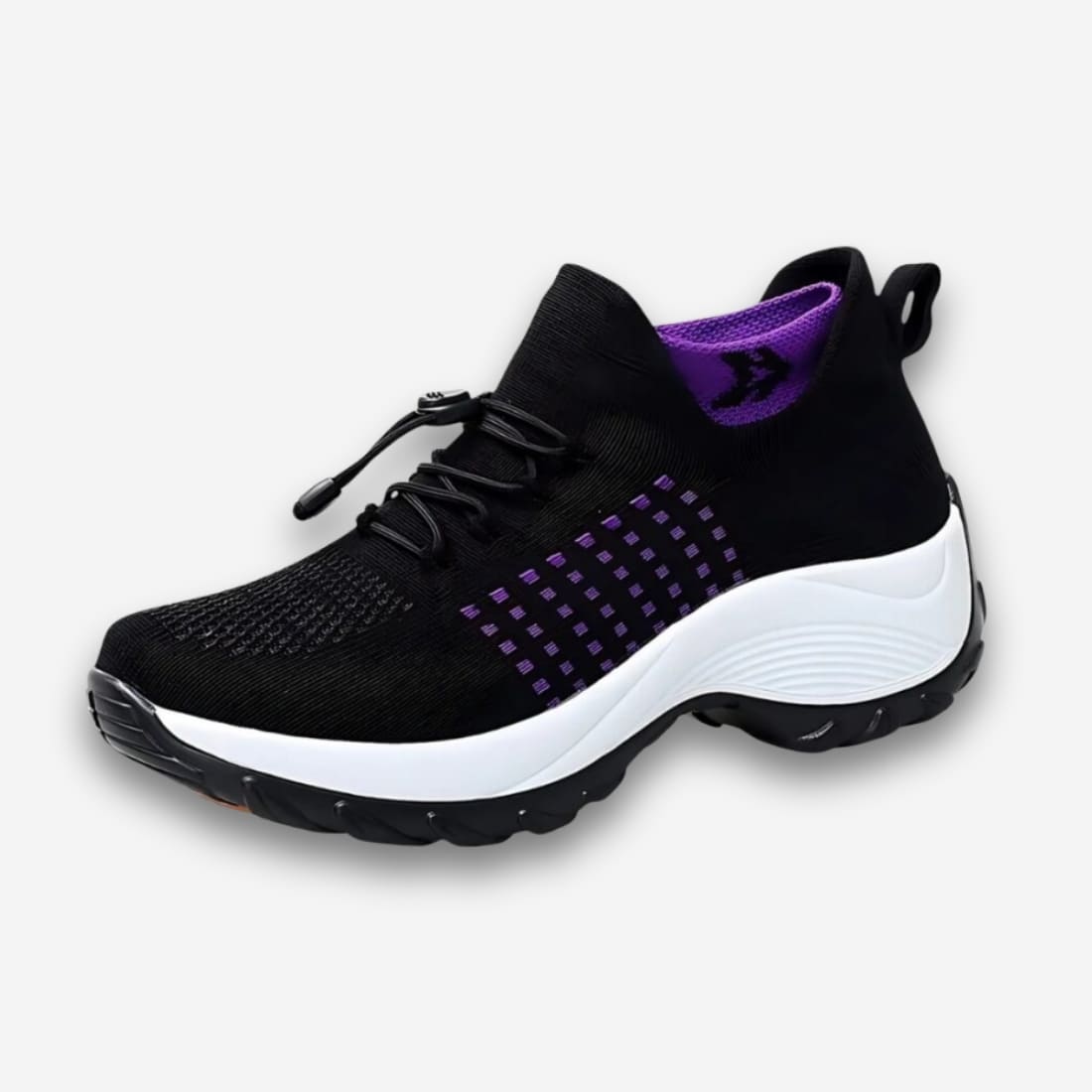 Baskets orthopédiques pour femme avec lacets élastiques et clip d'ajustement. De couleur noire avec un effet chaussette violette se trouve sur le col de la chaussure. Sur fond uni clair.