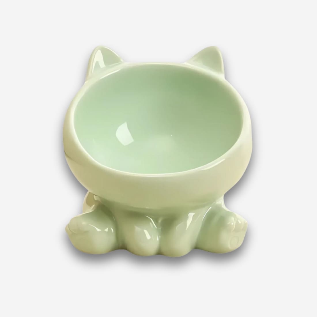 Bol orthopédique pour chat en céramique colorée verte. Sa forme : un chat assis. Sur fond uni clair.