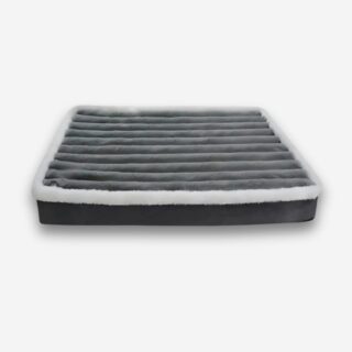 Lit orthopédique pour chien à mémoire de forme de couleur grise épais avec le contour en peluche blanche. Sur fond uni clair.