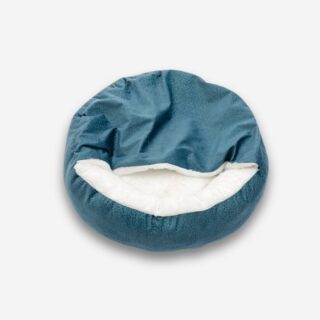 Lit orthopédique pour chien avec couverture intégrée. De forme ronde bleu turquoise avec l'intérieur blanc en peluche. Sur fond uni clair.