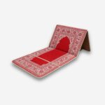Tapis de prière orthopédique rouge et blanc, replié de façon à former un dossier, vu de trois quarts, sur fond neutre.