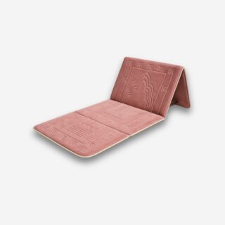 Tapis de prière rose avec dossier repliable et motifs en relief, vu de 3/4, sur fond neutre.