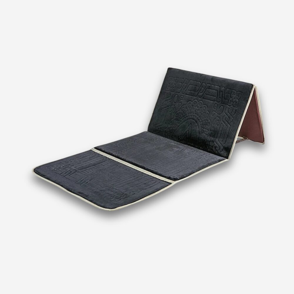 Tapis de prière orthopédique noir avec soutien dorsal repliable, sur fond neutre.