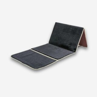 Tapis de prière orthopédique noir avec soutien dorsal repliable, sur fond neutre.
