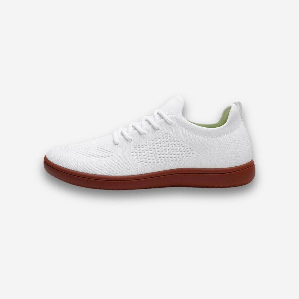 Chaussures blanches en toile avec lacets, semelle en caoutchouc marron, vue de profil, sur fond neutre blanc.