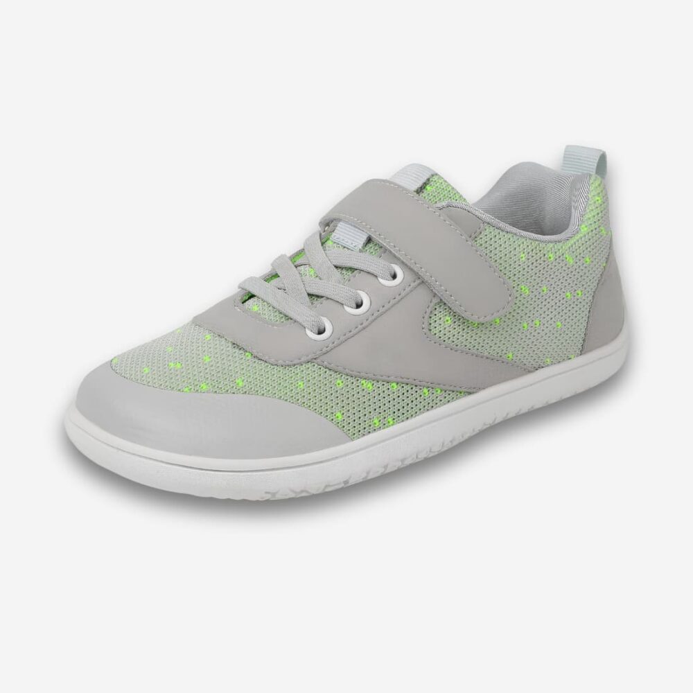 Chaussures orthopédiques enfant pour pied larges de couleur grise avec quelques touches de vert. Avec effet lacets et scratch. Sur fond gris très clair.