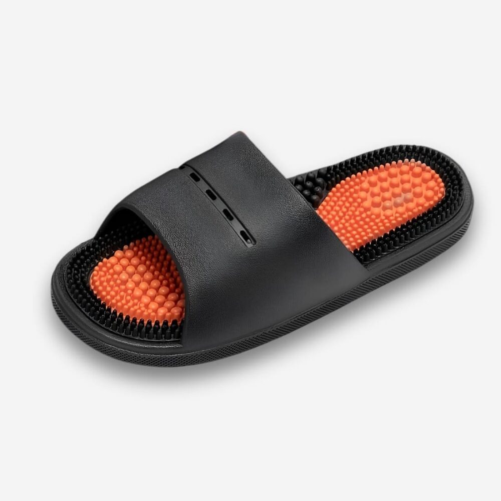 Claquettes orthopédiques massantes pour homme de couleur noire avec la semelle intérieure à picots oranges. Sur fond gris très clair.