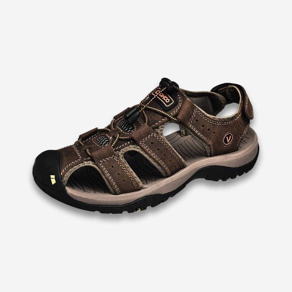 Une sandale orthopédique homme respirante en cuir de couleur marron foncée, vue de profil sur on fond gris très clair uni.