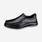 Une chaussure orthopédique homme style mocassin de couleur noire, vue de profil sur un fond gris très clair uni.