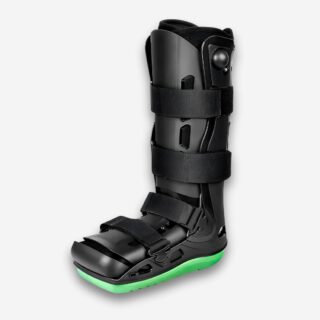 Bottes orthopédiques à coque intégrale de couleur noire et rigide. Le dessous est vert fluo. Quatre sangles ajustables noires. Sur fond uni clair.