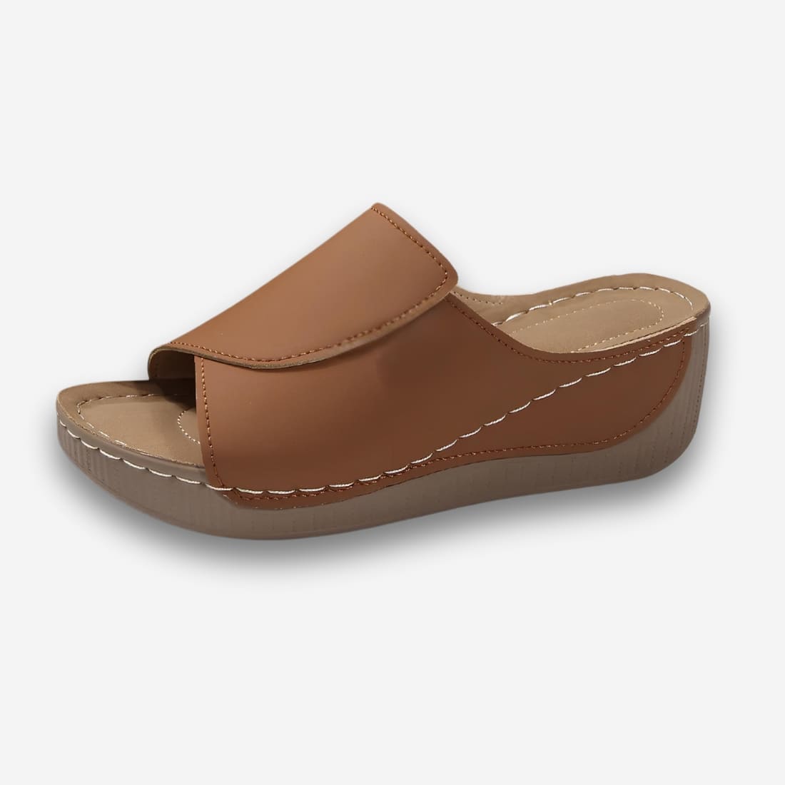 Mules orthopédiques compensées et ergonomiques pour femme de couleur marron avec une bande large au dessus du pied. Sur fond uni clair.