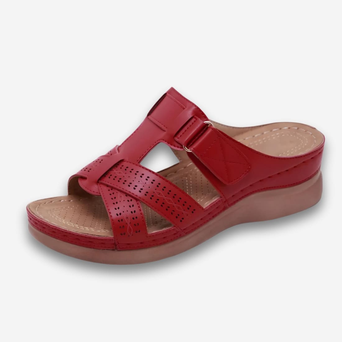 Mules orthopédiques pour femme avec boucle ajustable de couleur rouge et semelle compensée. Sur fond uni clair.