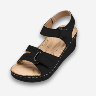 Sandales orthopédiques compensées pour femme de couleur noire avec une bride sur la cheville. Sur fond uni clair.