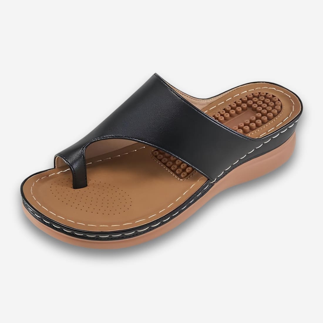 Sandales orthopédiques ouvertes pour femme talon massant de couleur noire avec une semelle compensée et des picots massant au talon. Sur fond gris très clair.