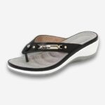 Tongs orthopédiques femme compensées au design élégant de couleur noir avec des détails en métal sur la bride. La semelle compensée est blanche. Sur gris très clair.