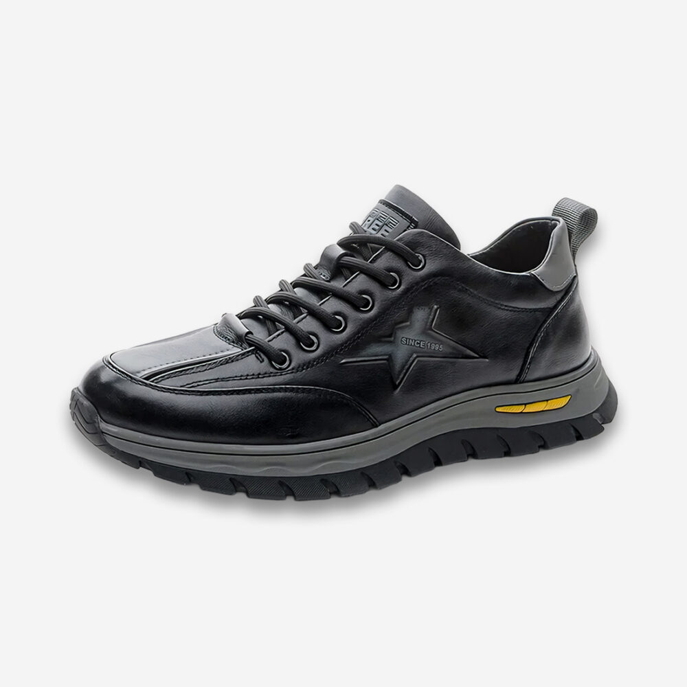 Une basket orthopédique homme à amortisseur magnétique, de couleur noire et gris foncé sur un fond gris très clair uni.