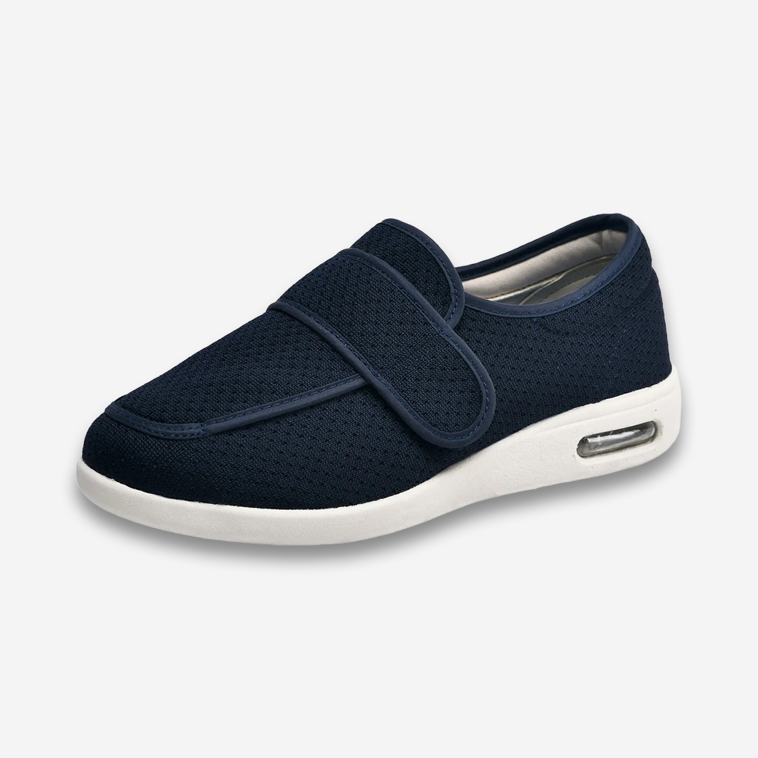 Un chausson orthopédique pour homme chaud et confortable bleu avec une semelle blanche et un coussin d'air intégré au talon, vu de 3/4 sur un fond gris très clair uni.