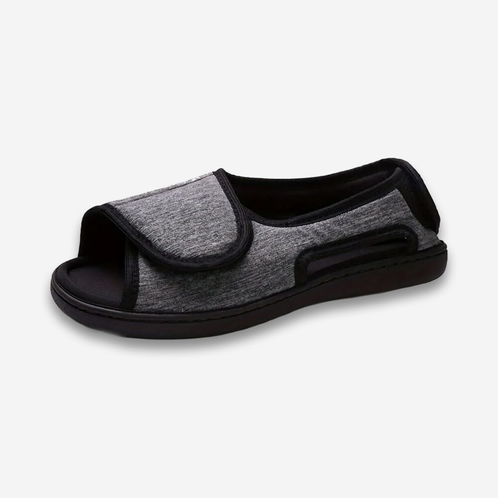 Un chausson orthopédique homme à large bande de couleur grise et noire, vu de profil sur un fond gris très clair uni.