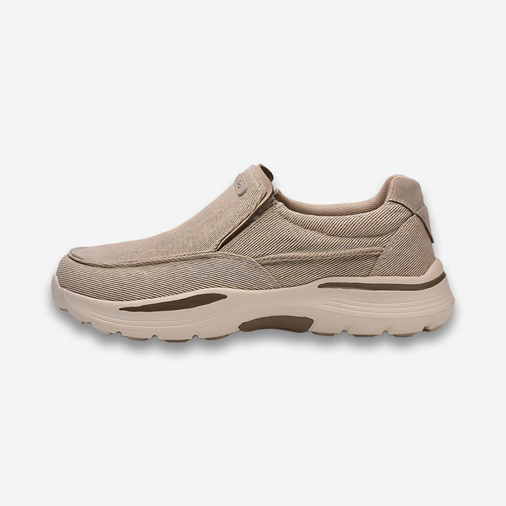 Une chaussure orthopédique homme en toile de couleur beige avec une semelle épaisse plus clair avec des inserts marrons, vue de profil sur un fond gris très clair uni.
