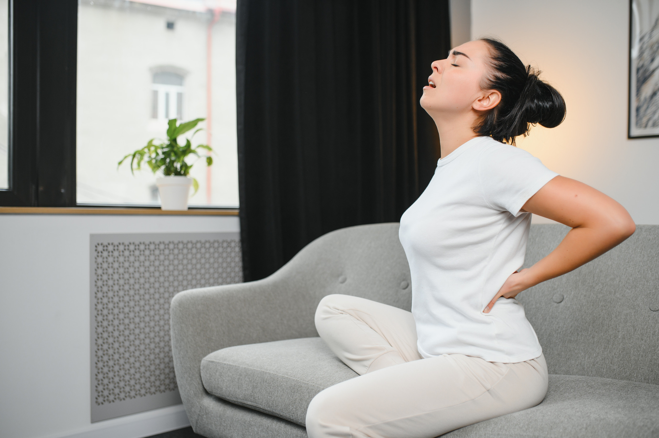 Femme dans son canapé assise ayant mal au dos