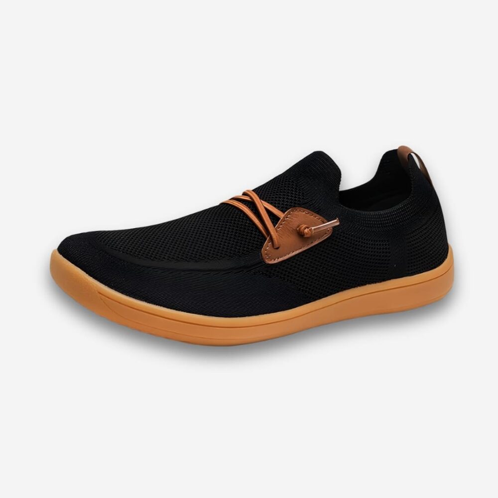 Chaussures orthopédiques femme pieds larges en maille respirante effet lacets. Le tissu est noir, la semelle marron et les faux lacets marrons. Sur fond gris très clair.