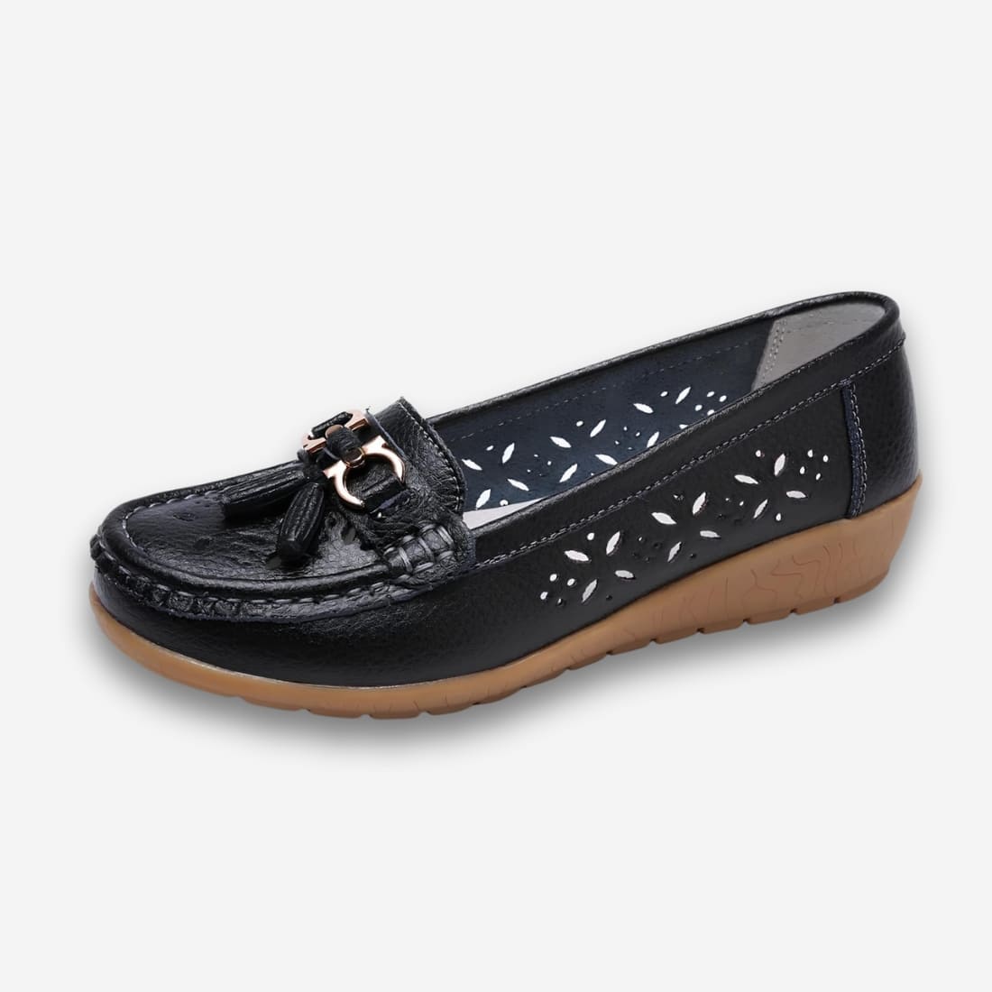 Chaussures orthopédiques mocassins à gland en cuir ajouré pour femme de couleur noire avec une semelle marron en caoutchouc. Sur fond gris très clair.