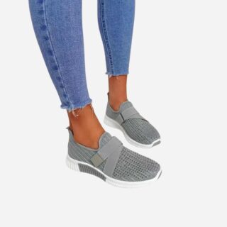 Bas des jambes d'une femme portant un jean slim et des baskets orthopédiques grises souples avec scratch sur le côté.